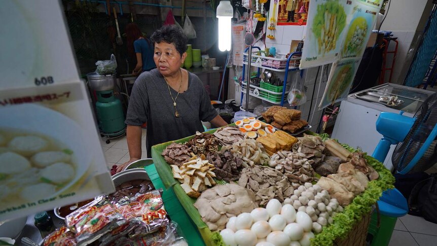 Woman sells food in a market place in Bangkok