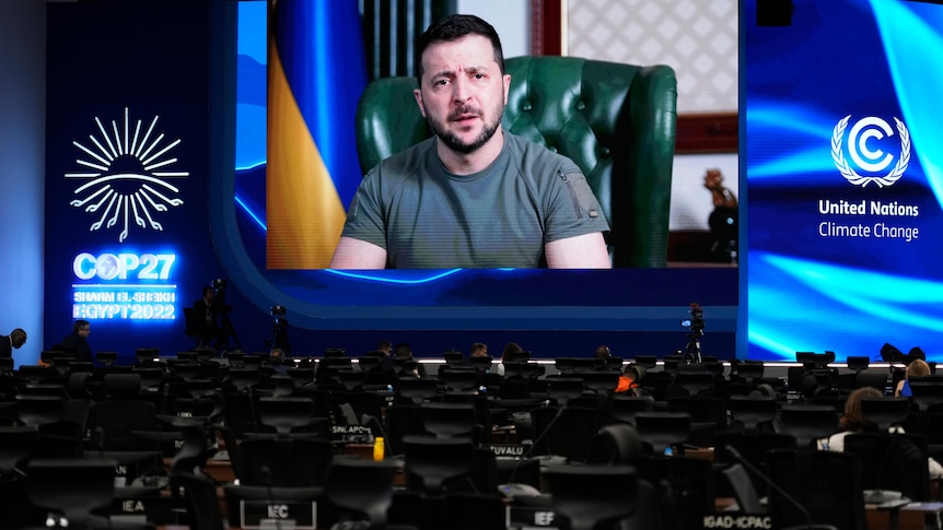 A man in green shirt on screen at a conference.