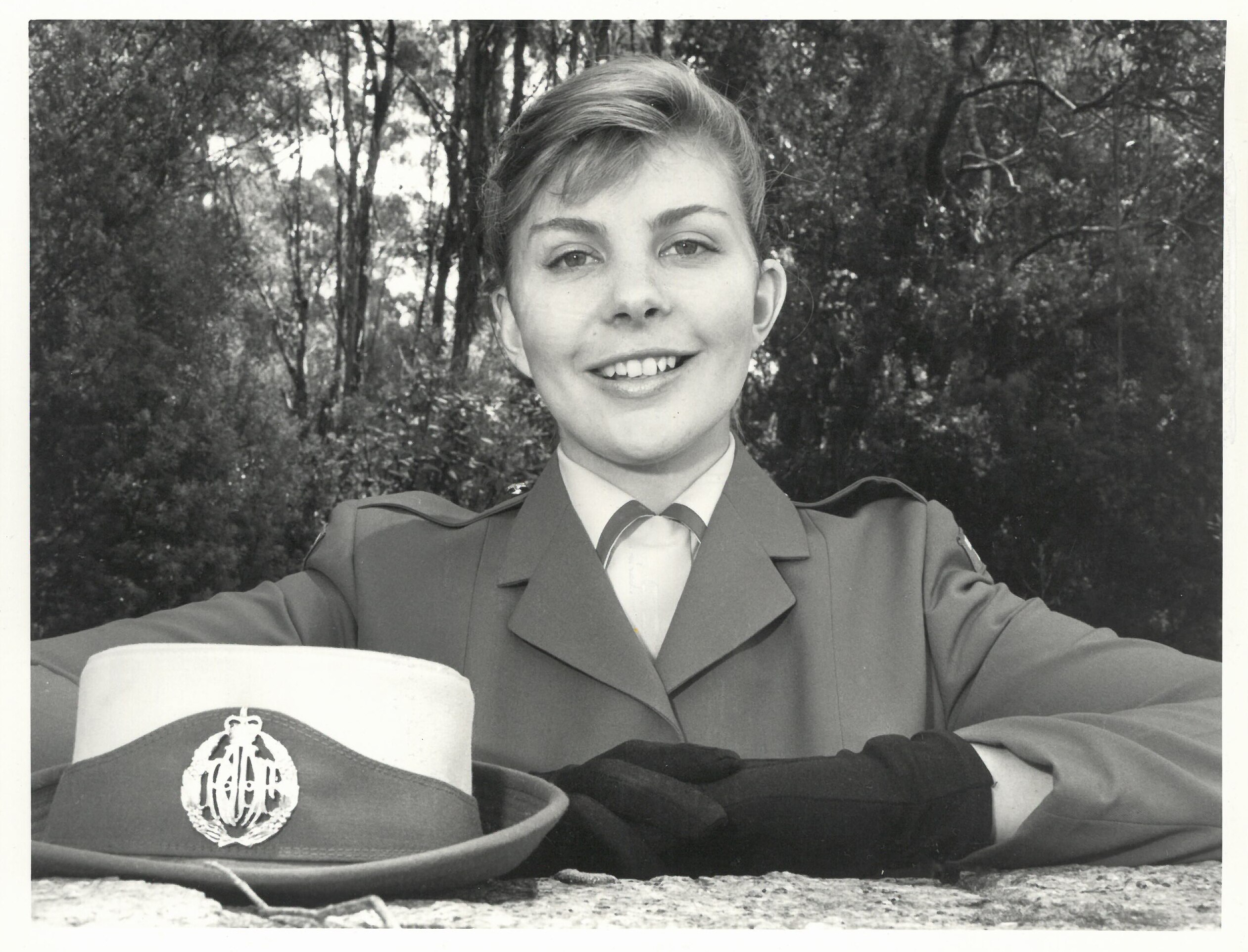 A scanned black and white photo shows a young woman in uniform, wearing gloves 