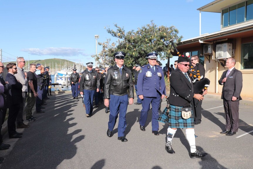 A line of police march behind a piper