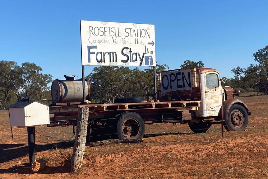 A vintage truck parked on a rural property is mounted with a sign that says Rose Isle station Farm Stay.