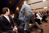 Security officers restrain a man after he rushes John Howard