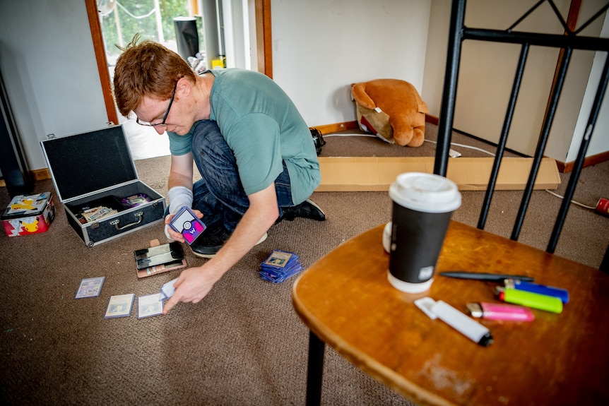 A young man laying cards on the floor.