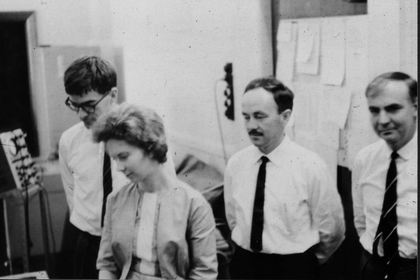 The four members of the CSIRAC staff in the lab looking towards the computer, which is out of shot