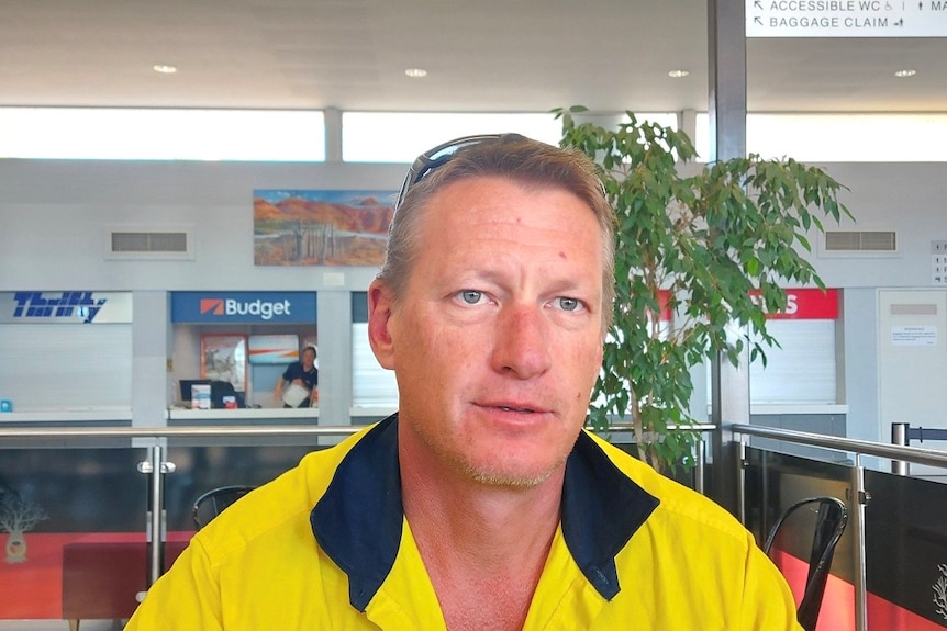 A man wearing yellow high vis clothing sits in Kununurra Airport