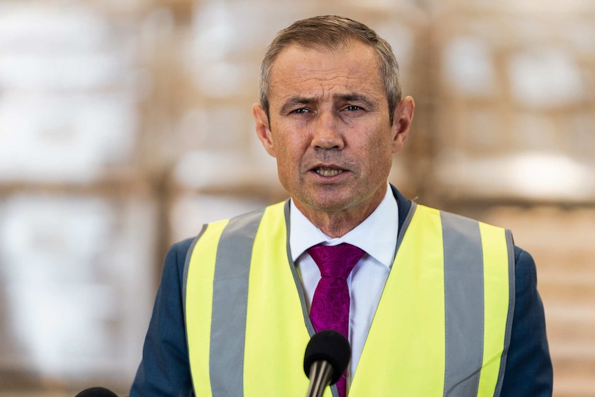 A head and shoulders shot of WA Health Minister Roger Cook speaking during a media conference wearing a hi-vis vest.