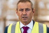 A head and shoulders shot of WA Health Minister Roger Cook speaking during a media conference wearing a hi-vis vest.
