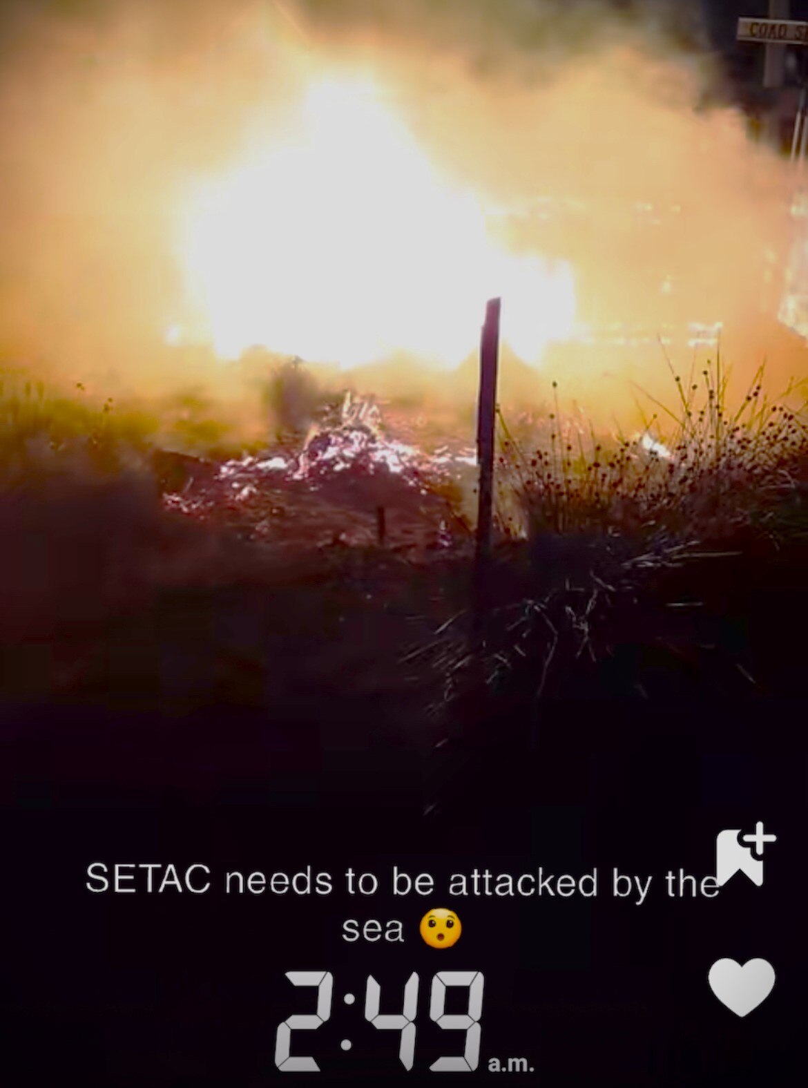 Still from video of bark hut on fire.