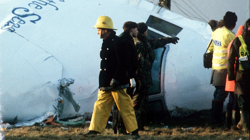 Rescue workers are standing around the wreckage of Pan Am flight 103.