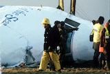 Rescue workers are standing around the wreckage of Pan Am flight 103.