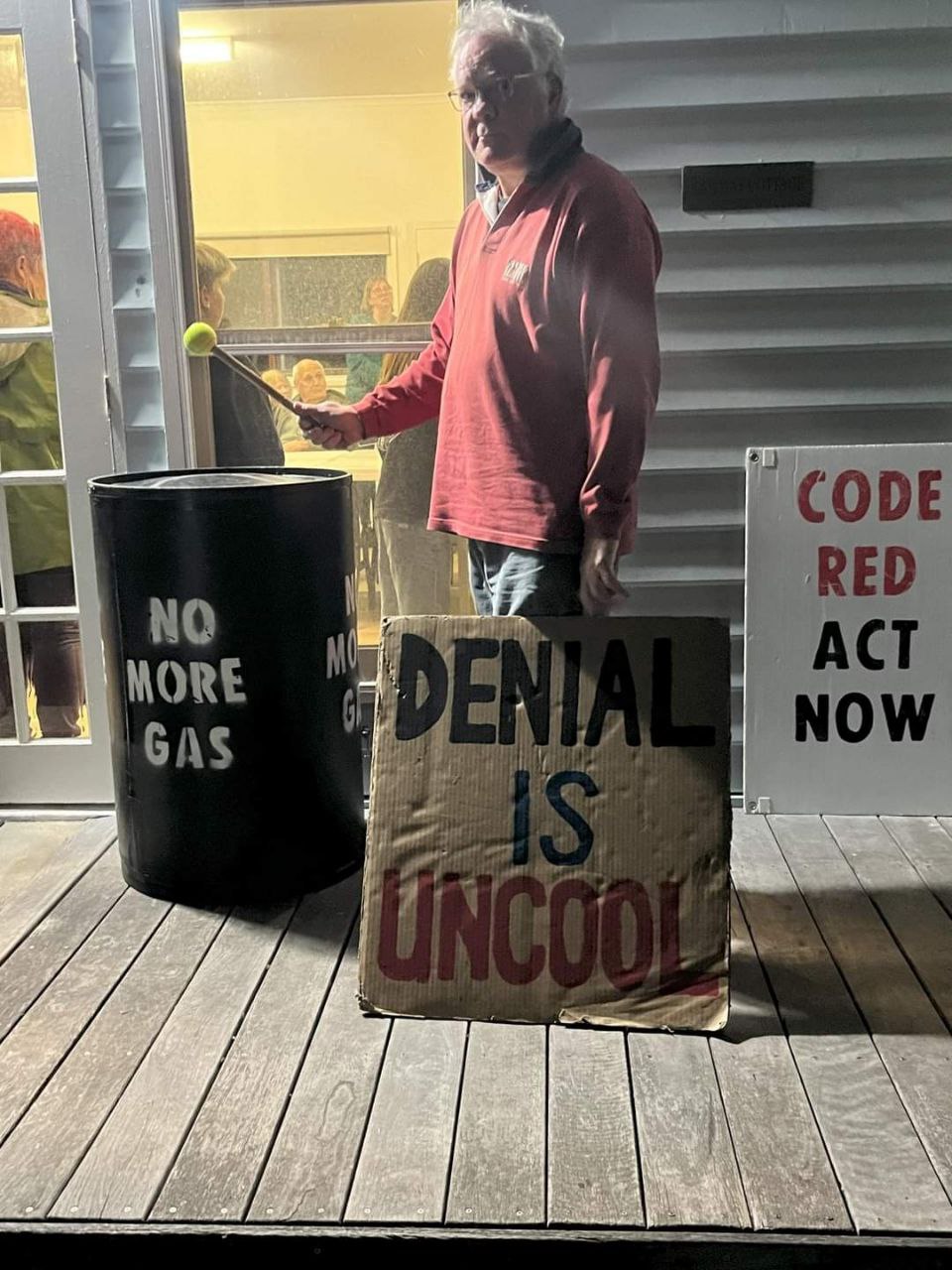 Man stands outside a community meeting surrounded by anti blasting signs 