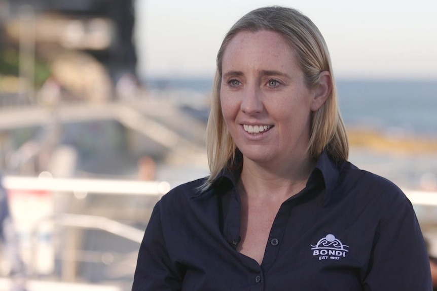 A woman in a navy shirt sits, smiling off camera.