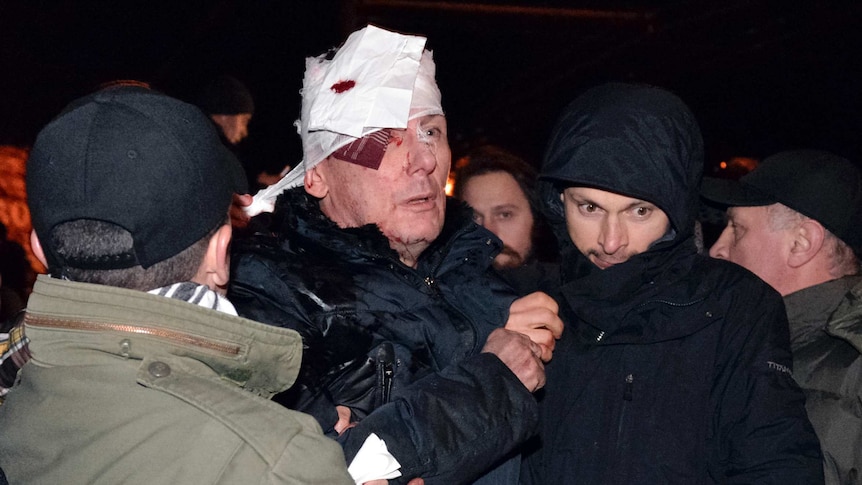 Ukraine's opposition leader Yuriy Lutsenko receives medical help after clashes with riot police near a court in Kiev.
