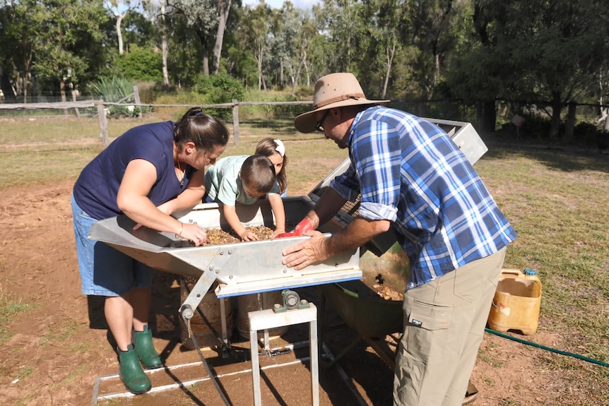 The Evans family sieves dirt through a large, square contraption