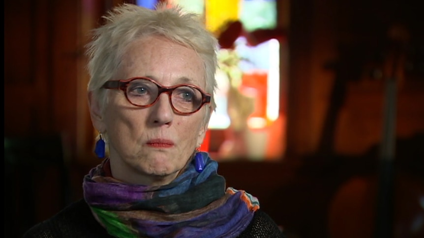 A woman in glasses speaks to a journalist.