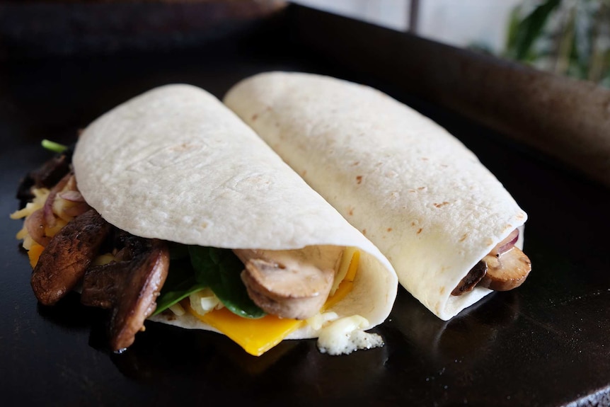 Two mushroom quesadillas sit on a flat grill to melt the cheese and crisp up the tortillas to depict dinner recipe.