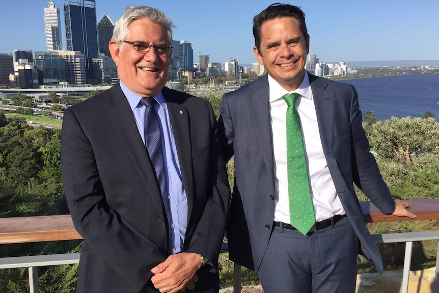 A smiling Ken and Ben Wyatt standing side by side at Kings Park with the Perth city CBD and Swan River in the background.