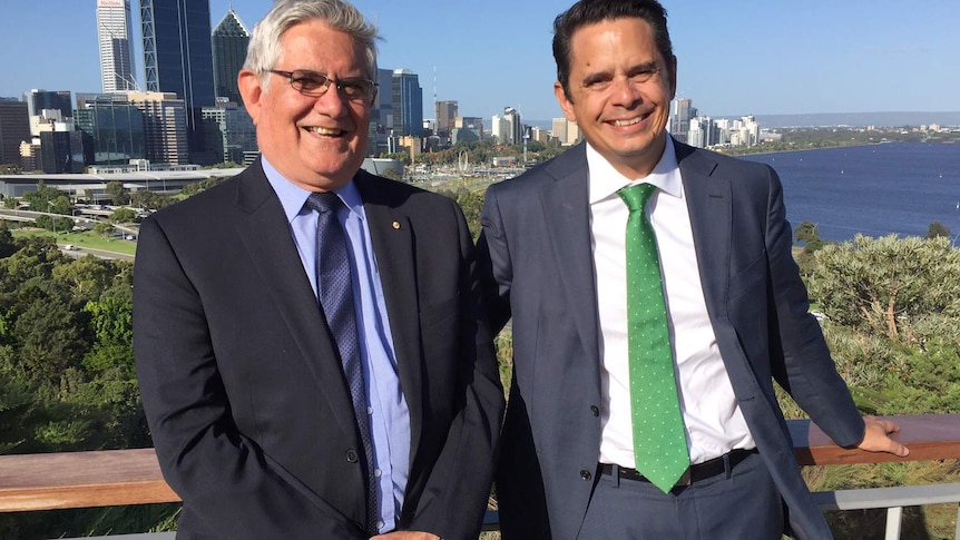 A smiling Ken and Ben Wyatt standing side by side at Kings Park with the Perth city CBD and Swan River in the background.