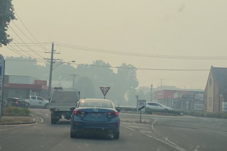 Cars approach a roundabout under intensely smoky skies in Wangaratta.