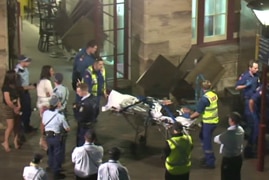 Police and paramedics escort a woman on a stretcher