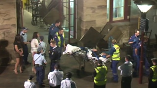 Police and paramedics escort a woman on a stretcher