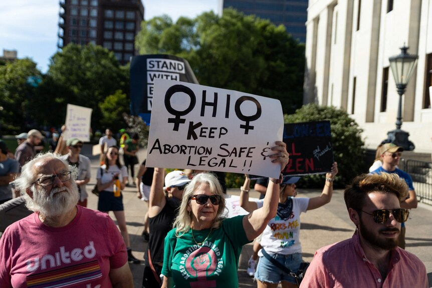 Women hold signs about keeping abortion safe and legal.