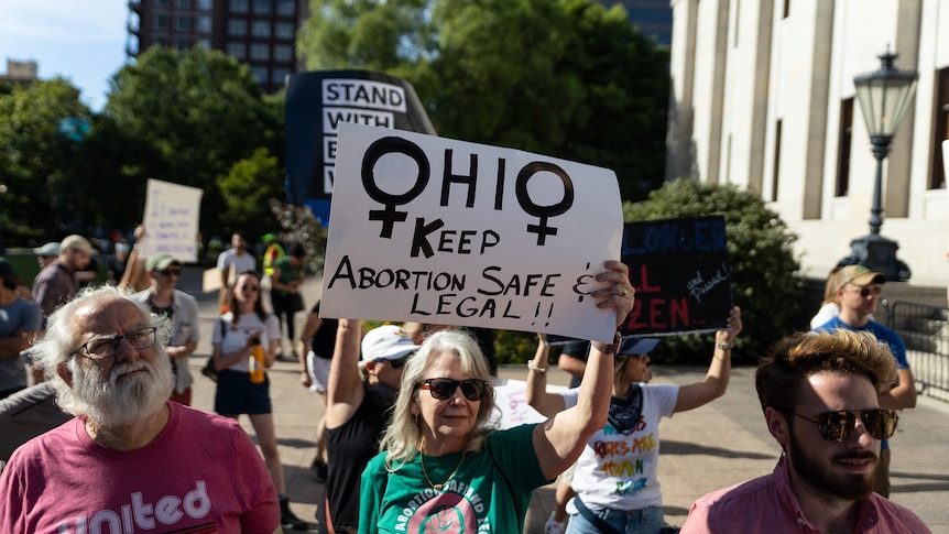 Women hold signs about keeping abortion safe and legal.