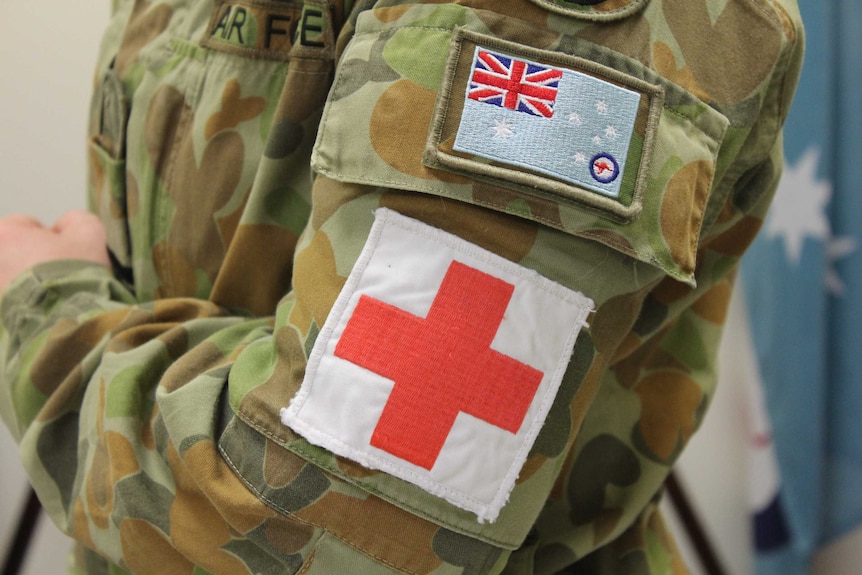 The torso of a camouflaged Royal Australian Air Force uniform including red cross and RAAF flag.