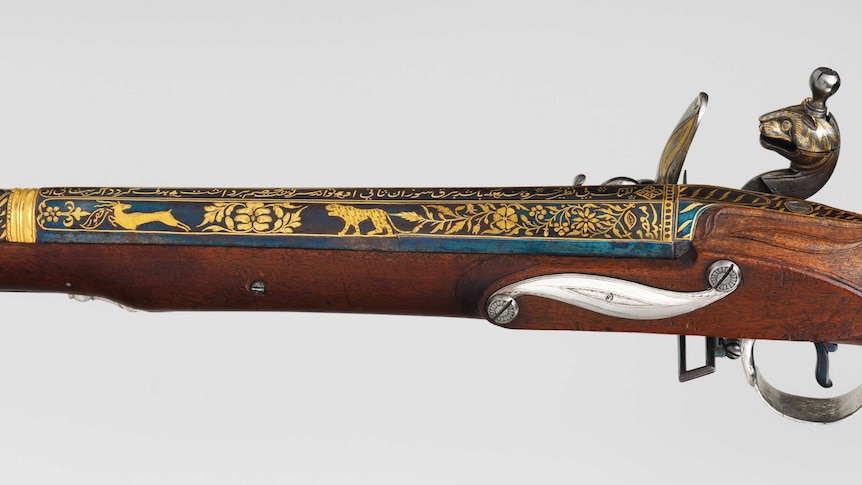 A blunderbuss decorated in gold with tigers, flowers, and tiger stripes. The cock of the rifle is shaped like a tiger's head.