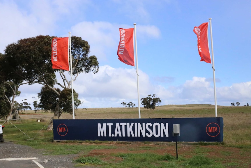Large signs reading 'Mt Atkinson' with flags outside green paddocks that will become a new suburb in Melbourne's west