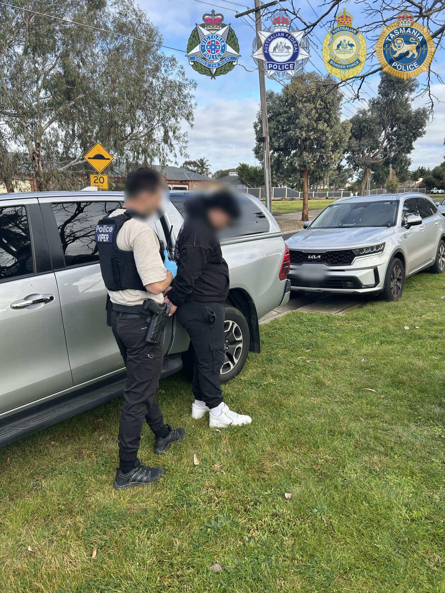 Police officer arrests a person in black top.