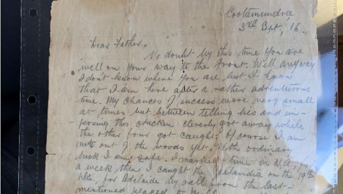 A very old letter on yellow paper is photographed inside a plastic sleeve.