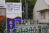 A sign for a school with buildings behind