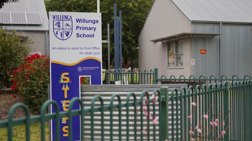 A sign for a school with buildings behind