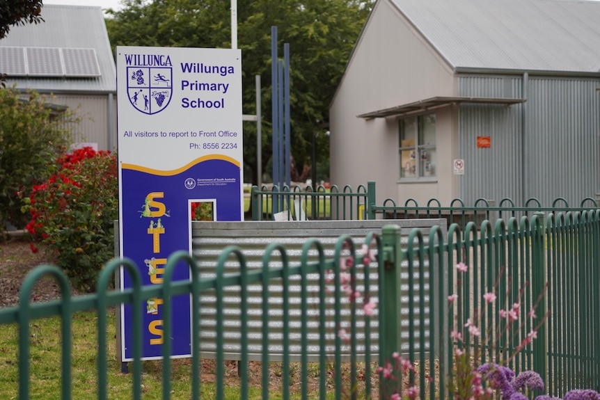 A sign for a school with buildings behind