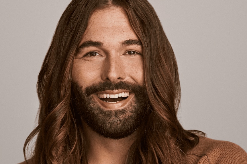 Head shot of a person with a beard and long brunette hair who appears warm and smiling.