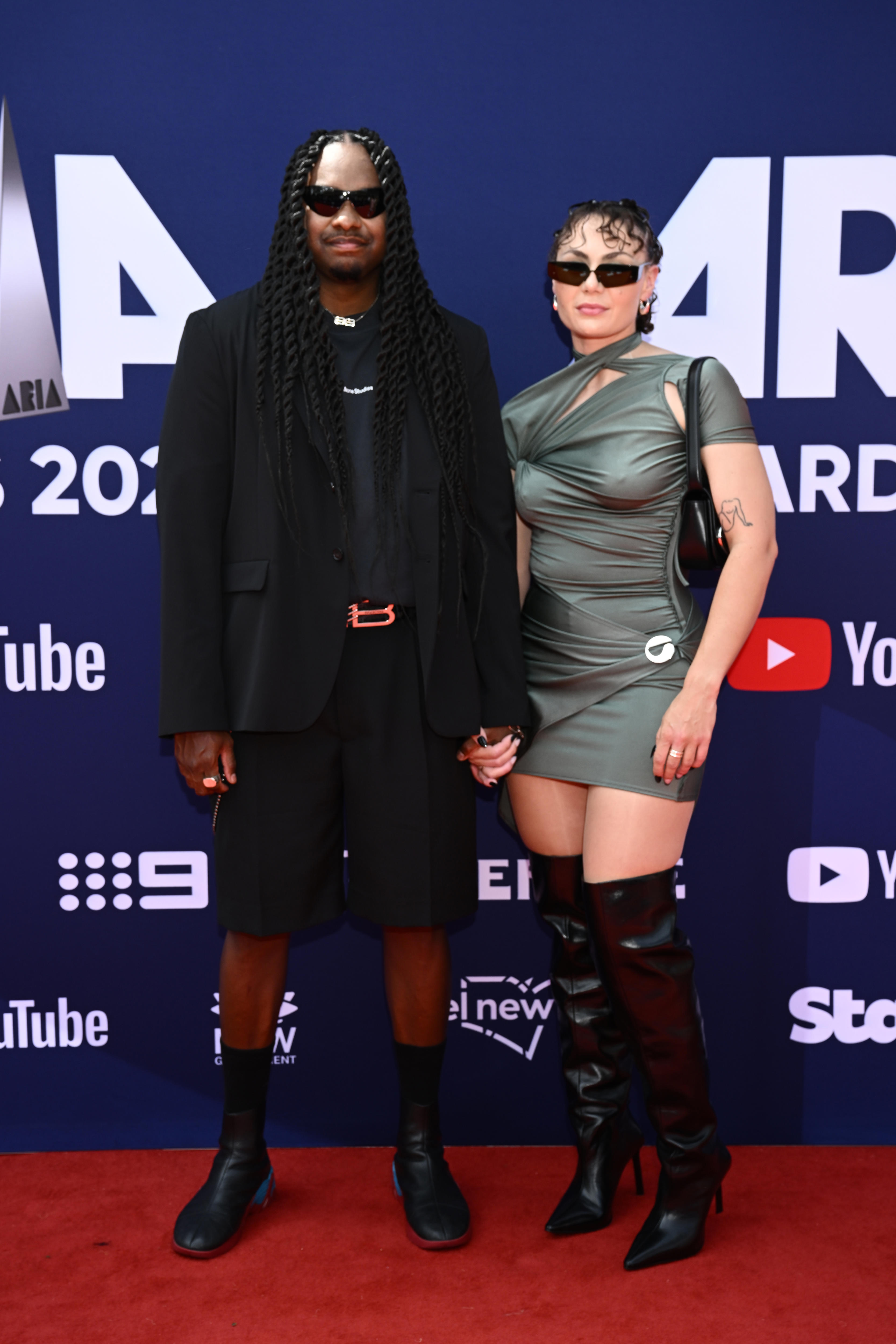 A man wearing a black suit holding hands with a lady in a dress