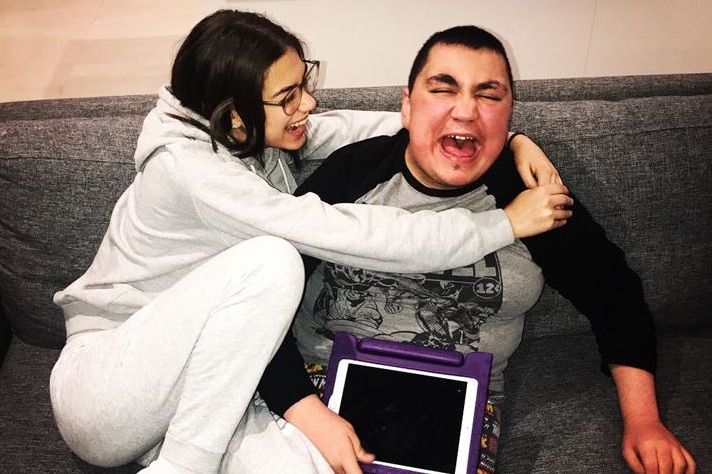 A smiling woman hugs her brother.