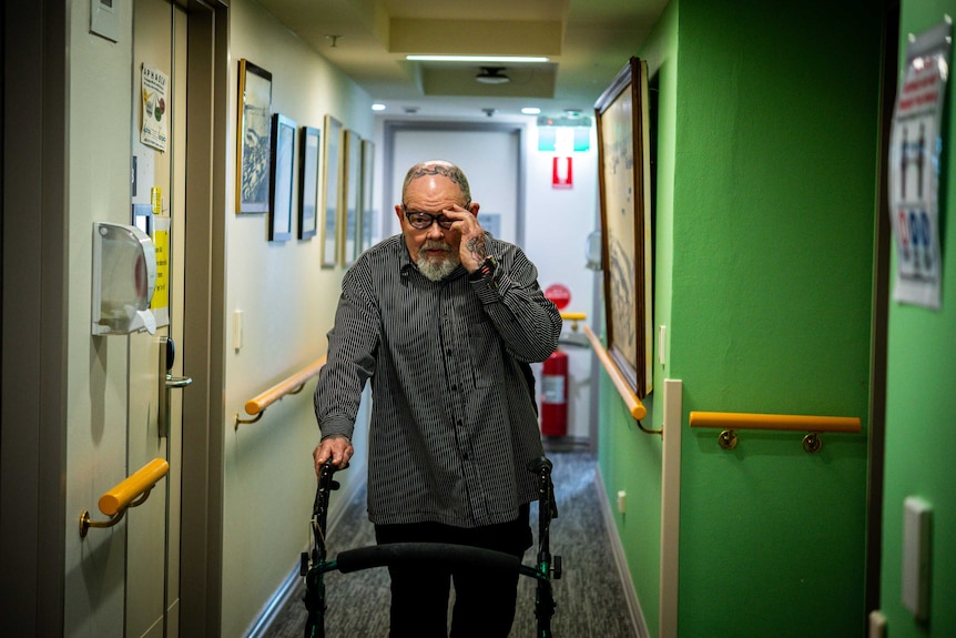 Geoffrey Ostling walks down a hall in aged care.