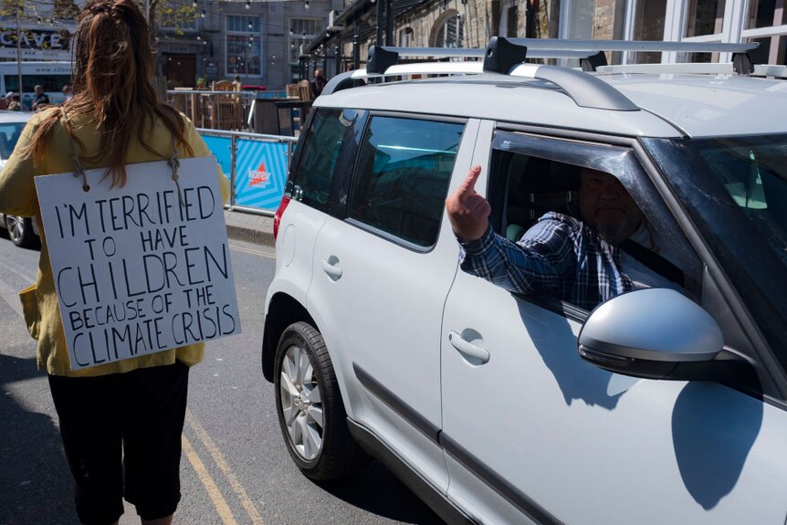 A driver raising his middle finger at a protester.