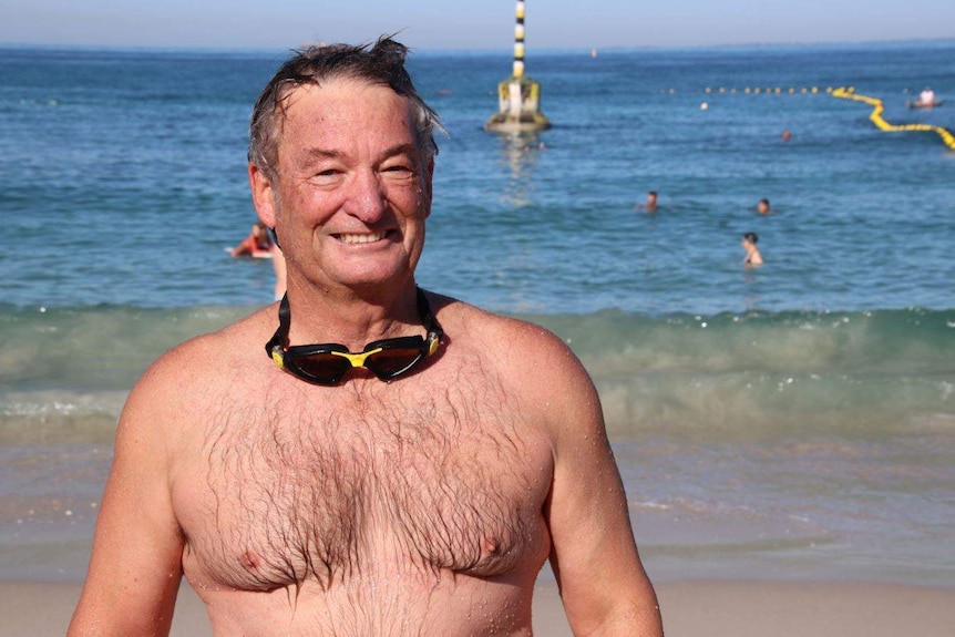 Chris Chalwell with his goggles around his neck, the shark net in the background at Cottesloe Beach.