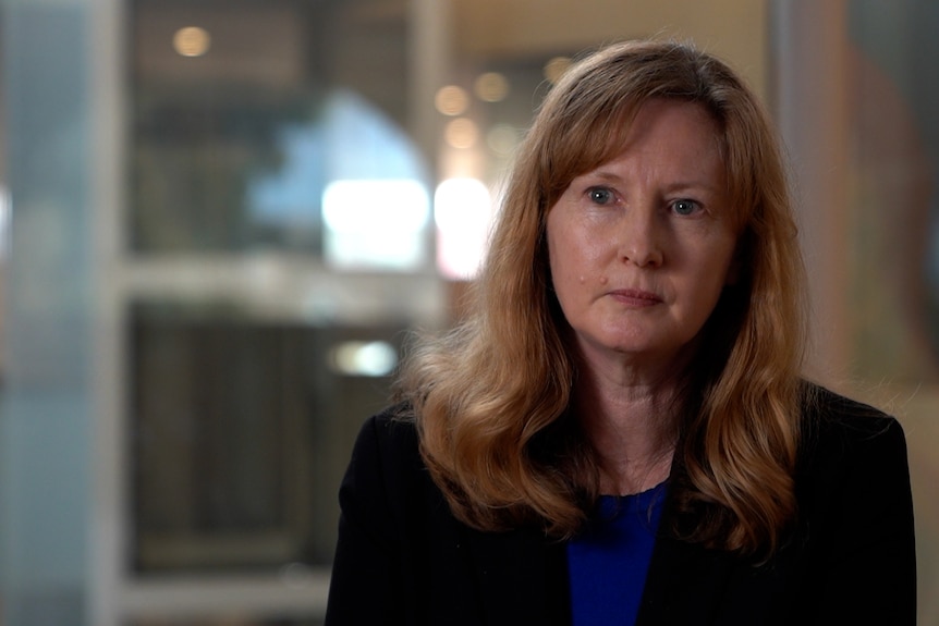 Woman with shoulder length strawberry blonde hair wearing a black jacket