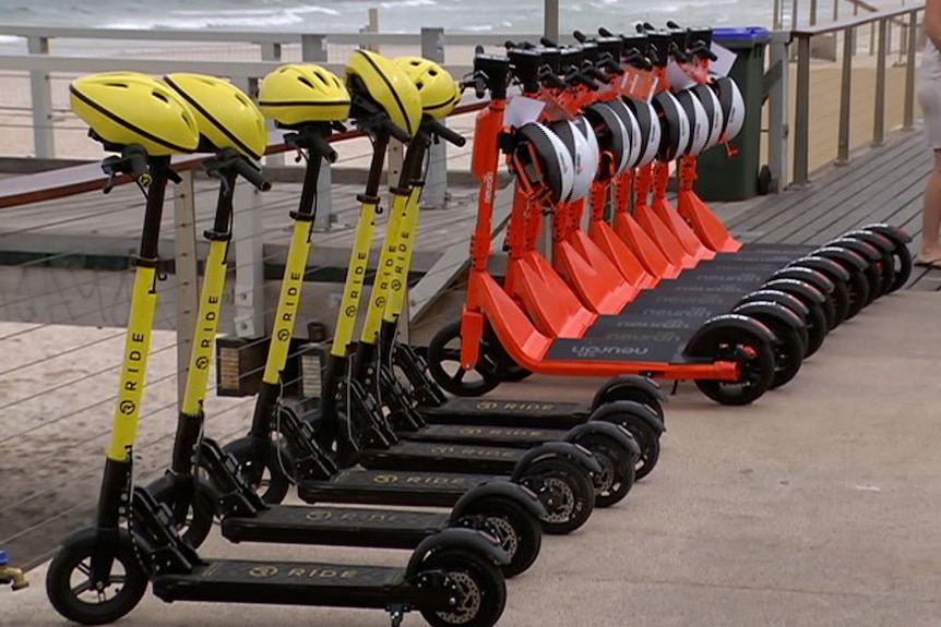 A line-up of yellow and red scooters with helmets