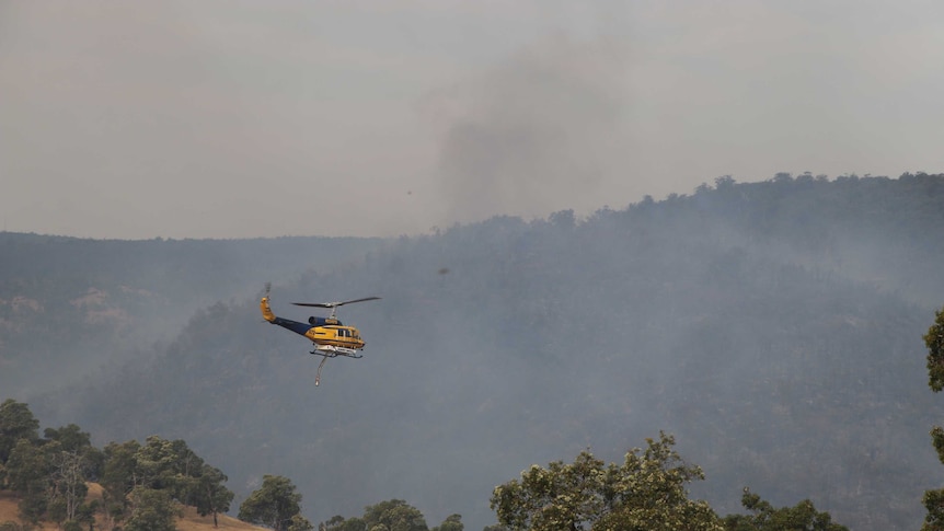 A helicopter flies through smoky skies at Bullsbrook.