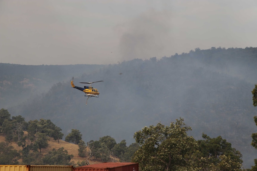 A helicopter flies through smoky skies at Bullsbrook.