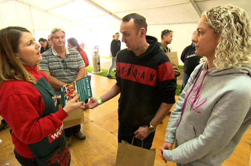 A Bunnings employee hands a brochure to a person.