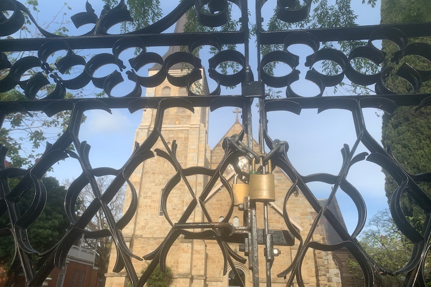 A chain is wrapped around back gates and a large church sits in the background