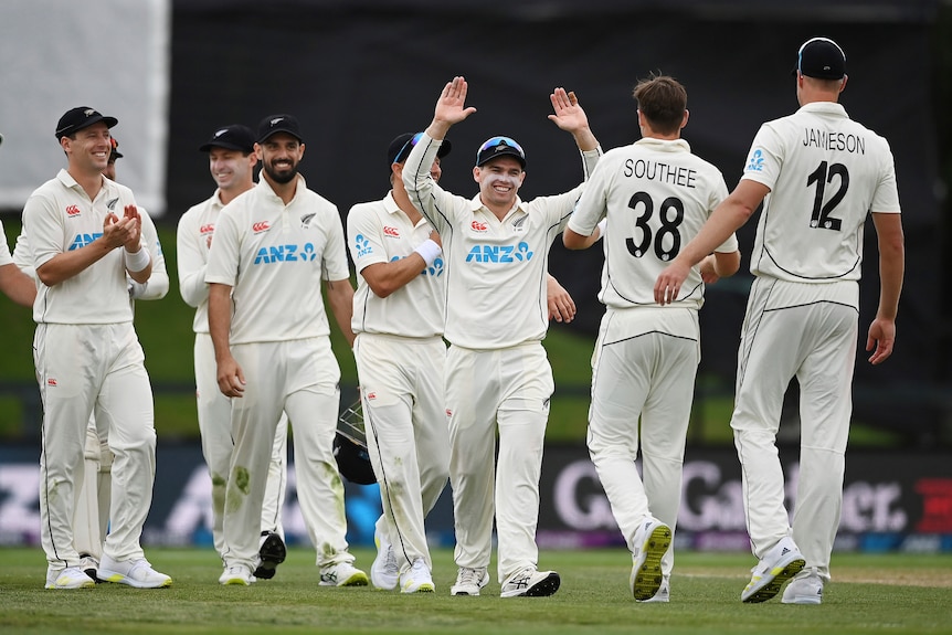 New Zealand captain Tom Latham celebrates with his team raising his arms as Tim Southee approaches