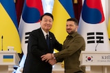 South Korean President Yoon Suk Yeol shakes hands with Ukraine President Volodymyr Zelenskyy.