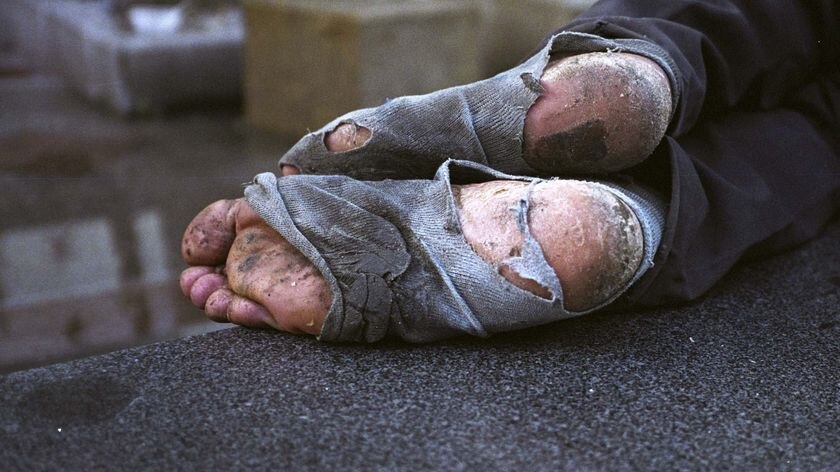 A homeless man naps on a street
